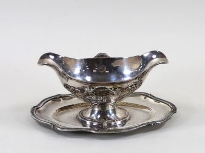 une assiette en argent ancien posée sur une soucoupe, le tout sur un fond blanc