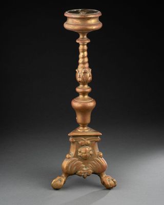 un bougeoir ancien en laiton surmonté d'un porte-bougie