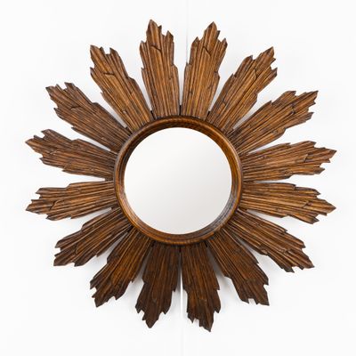 une photo d'un miroir en bois en forme de soleil accroché au mur