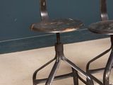 pair of industrial stools with backrests and foot rests against a blue painted wall