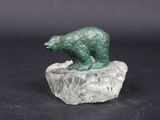 statue d'un ours vert posé sur un rocher, sur fond noir