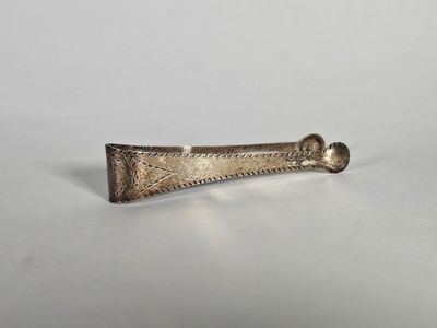 un vieil objet métallique argenté posé sur une surface blanche