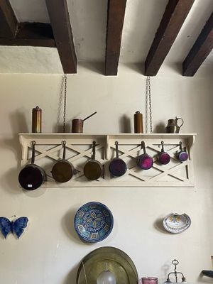 une photo d'une cuisine où des casseroles et des poêles sont suspendues au plafond