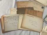 a pile of old letters and envelopes sitting on a bed