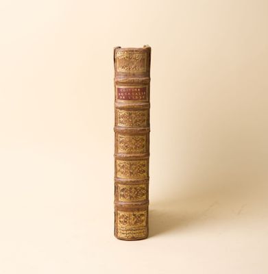 un vieux livre posé sur une table à côté d'un mur blanc