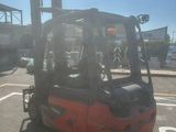 a red forklift truck parked in a parking lot