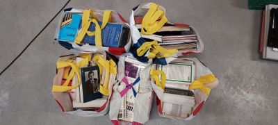 une pile de livres entourée d'un ruban jaune, posée par terre