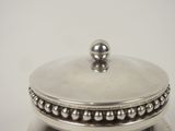 a silver container with beads on it on a table