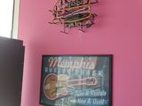 a pink wall with a neon sign and a picture of a doughnut shop