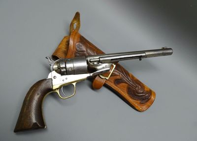 un vieux revolver dans un étui en cuir posé sur une surface grise