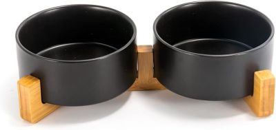 deux bols noirs posés sur des socles en bois, sur une surface blanche