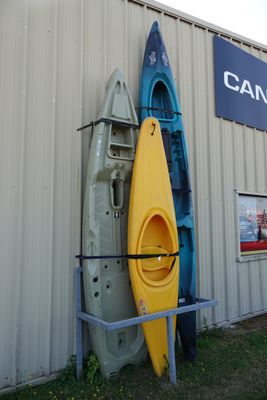 Plusieurs kayaks sont alignés contre un mur devant un bâtiment