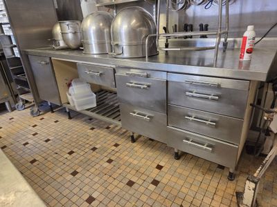 une grande cuisine en inox avec de nombreuses casseroles et poêles posées sur le plan de travail