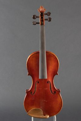 an old violin sitting on a stand against a gray background