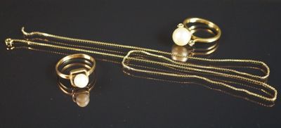 deux bagues et un collier posés sur une surface noire