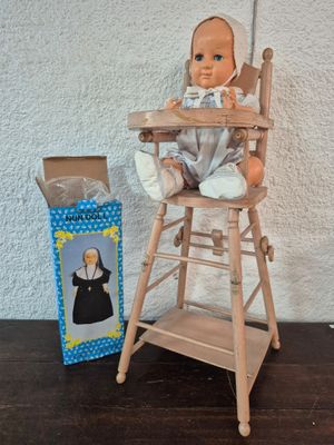 une poupée assise dans une chaise haute à côté d'une boîte
