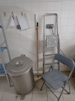 plusieurs chaises et une poubelle dans une pièce carrelée de blanc