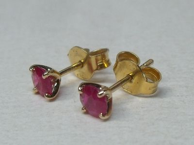 une paire de boucles d'oreilles à clous ornées de pierres roses, posées sur une surface blanche