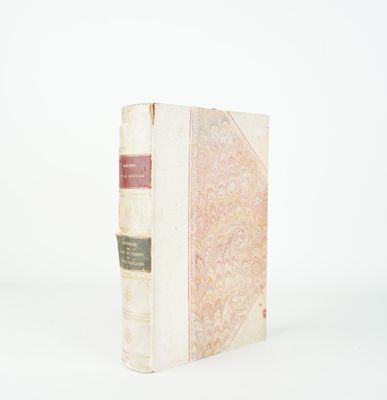 un vieux livre posé sur une table blanche à côté d'un mur blanc