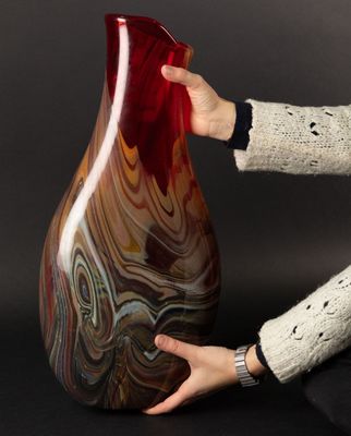 woman sitting on the floor holding a large red vase in her hands