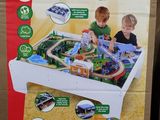 two children playing with a wooden train table in the store