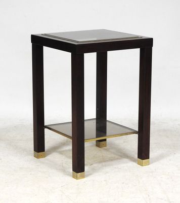 une table d'appoint noire et dorée avec une étagère en verre