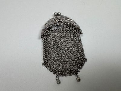 un petit sac à main en métal, muni d'une chaîne, posé sur une surface blanche