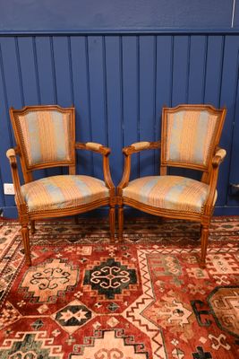 une paire de chaises en bois avec des assises rembourrées, dans une pièce bleue