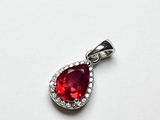 un gros plan d'un pendentif rouge en forme de cœur posé sur une surface blanche