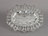 une assiette ancienne en argent, ornée d'un motif floral sur le bord