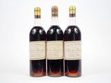 trois bouteilles de vin posées les unes à côté des autres sur une surface blanche