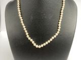 un collier de perles blanches sur un mannequin avec un fermoir en or