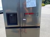 un réfrigérateur argenté posé sur une palette dans un parking