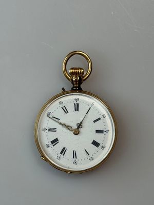 a gold pocket watch with roman numerals on the face