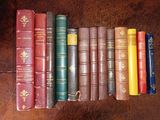 several old books are lined up on a brown leather surface