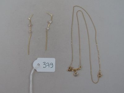 trois colliers en or et une paire de boucles d'oreilles avec une étiquette de prix