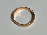 une bague en or posée sur une surface blanche
