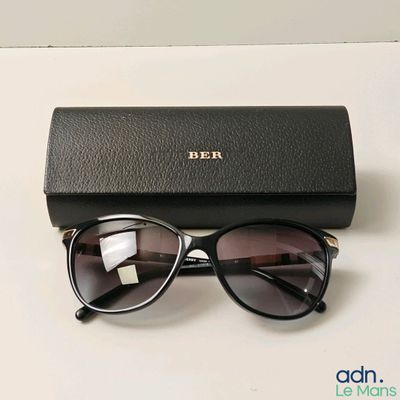 des lunettes de soleil noires aux verres marron posées sur une table blanche