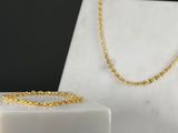 a close up of a gold necklace and bracelet on a marble block