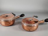 une paire de casseroles et poêles anciennes en cuivre avec des poignées noires