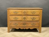 a wooden chest of drawers on a chevroned wooden floor