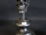 two metal skulls sitting on top of each other on a table
