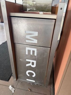 une boîte métallique sur laquelle est apposée une étiquette portant l'inscription « merc »
