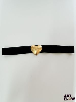 un gros plan sur un collier noir orné d'un cœur doré