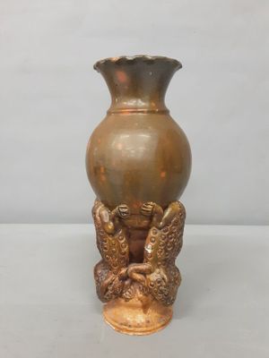a bronze vase sitting on a table with two birds on it