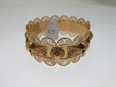 une photo d'un bracelet en or posé sur une surface blanche, avec une étiquette de prix
