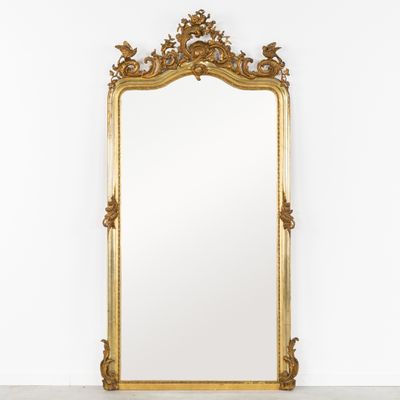 un miroir à cadre doré dans une pièce blanche aux murs blancs