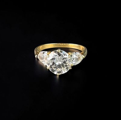 a yellow gold ring with three diamonds on a black background