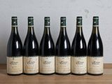 six bouteilles de vin sont alignées sur une table en bois