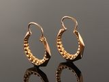 gold plated hoop earrings on a reflective surface
